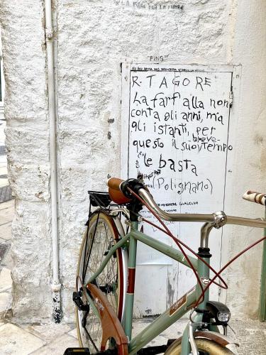a bike parked next to a wall with writing on it at Hotel San Giovanni in Polignano a Mare