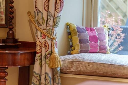 a couch with a pillow and a window at Morston Hall in Holt