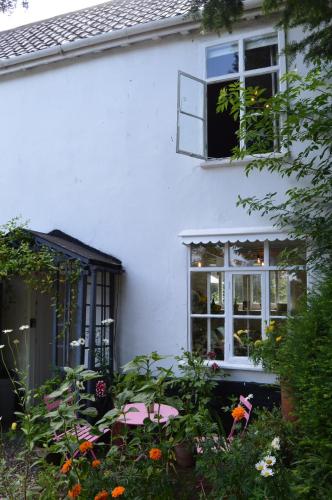 a white house with a window and some flowers at Countryside Tiny House in Roydon