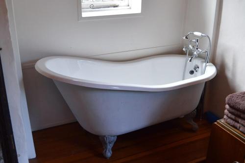 a white bath tub in a bathroom with a window at Countryside Tiny House in Roydon