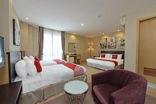 a hotel room with two beds and a chair at Collection O Melaka Near Dataran Pahlawan Formerly Ideals Hotel in Melaka