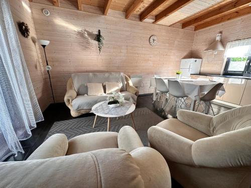 a living room with couches and a table and a kitchen at Domki Kalipso in Sarbinowo