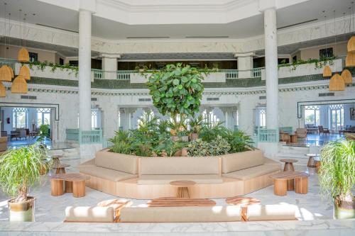a large lobby with a large plant in the middle at Hotel El Mansour Mahdia Thalasso & Spa in Mahdia