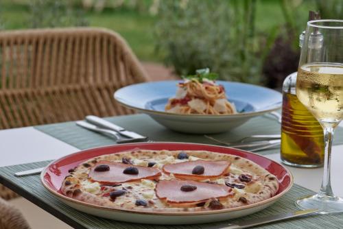 a table with a plate of pizza and a glass of wine at Atlantica Callisto in Ayia Napa