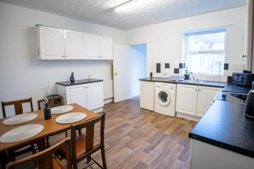 a kitchen and dining room with a table and a kitchen with a washing machine at Saint Nico in Carlisle