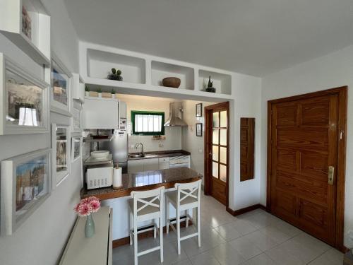 eine Küche mit weißen Wänden und einer Theke mit Hockern in der Unterkunft Casa Maresía in Playa Honda