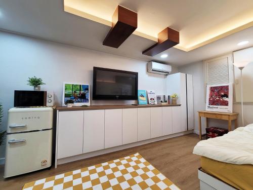 a kitchen with white cabinets and a flat screen tv at Residence YeoYu in Incheon
