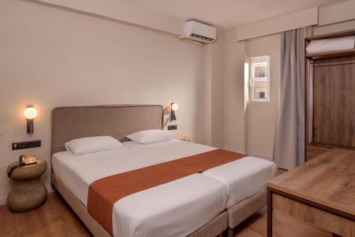 a bedroom with a large white bed and a desk at Zeus Hotels Ydoria Resort in Adelianos Kampos