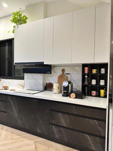 a kitchen with white cabinets and a black counter top at OLÉ Villa in Xiyu