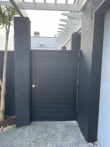 a black garage door with a white roof at Central City Haven in Auckland