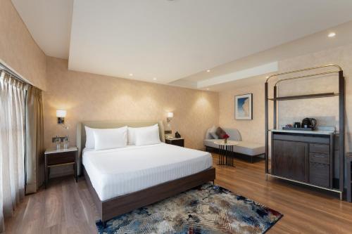 a bedroom with a large white bed and a mirror at Clarks Inn Suites Hyderabad Airport in Hyderabad