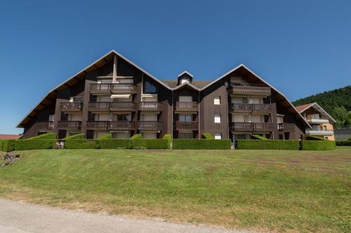 a large apartment building with a grass field in front of it at Au Coin des Souvenirs in Malbuisson