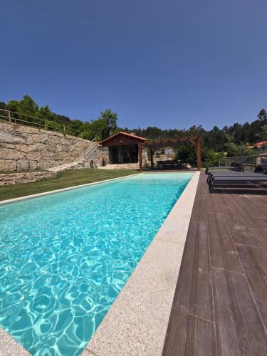 a swimming pool with blue water in front of a house at Casa Vale do Luar in Celorico de Basto