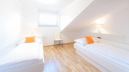 two beds in a room with white walls and wood floors at Appartement In Unterburg Am Klopeiner See in Unterburg am Klopeiner See
