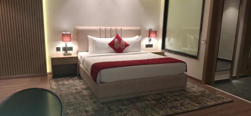 a bedroom with a bed and two tables and a mirror at Rosastays Hansi, Hisar in Hānsi