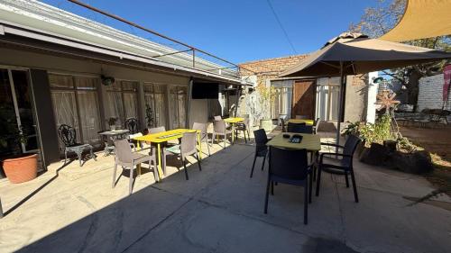 an outdoor patio with tables and chairs and an umbrella at Mar-Zel Guesthouse - Fam Room in Britstown