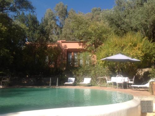a pool with a table and chairs and an umbrella at MAROC LODGE Atlas Mountain Retreat in Amizmiz