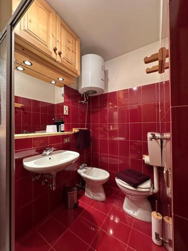 a bathroom with two sinks and a toilet and red tiles at Wood Peak Apartment in Semogo