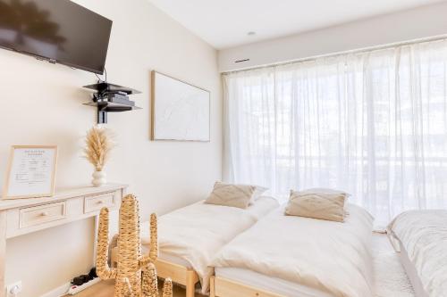Una habitación blanca con dos camas y una ventana. en Bohemian Nuance - 15 min from Orly - Calme & Elégance, en Antony