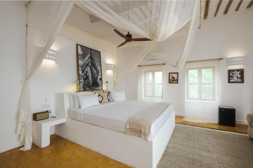 a white bedroom with a large bed with a ceiling at Dar Beach House - Michamvi in Michamvi