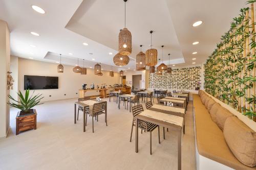 a restaurant with tables and chairs and a wall with plants at Lyxos Hotel in Kas