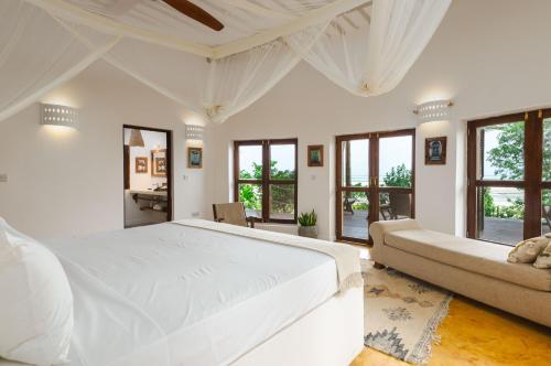 a white bedroom with a large bed and windows at Dar Beach House - Michamvi in Michamvi