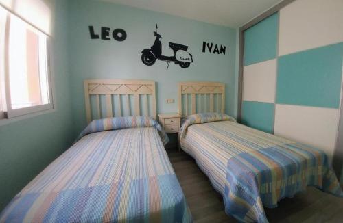 two beds in a room with a room with a vespa on the wall at CASA Dúplex Peñíscola in Peniscola