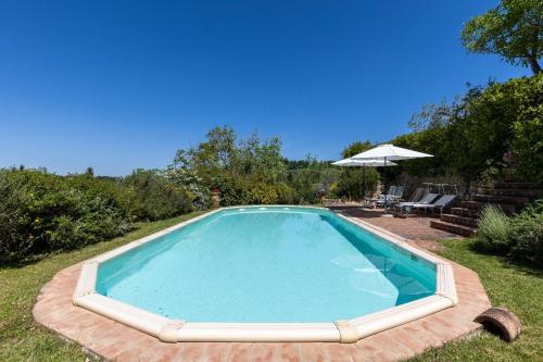 a swimming pool in a yard with an umbrella at Chianti Holidays, Il Poggetto da Alfina in Tavarnelle in Val di Pesa