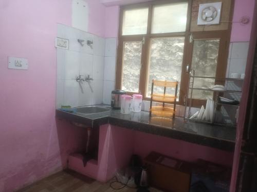 cocina rosa con fregadero y ventana en Habitat Cottages, en Bashist
