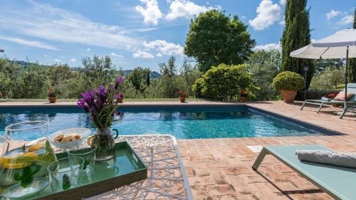 a pool with a table with a vase of flowers at Podere San Regolo in Scansano