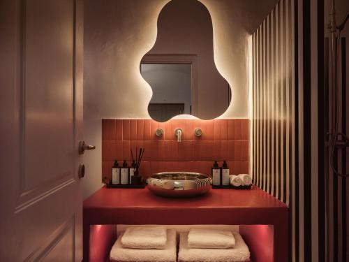 a bathroom with a red counter and a mirror at Neema Maison Finikia Santorini in Oia