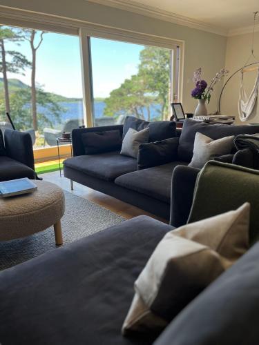 a living room with blue couches and a large window at Caragh Lake House - Lakefront Escape and Sauna in Killorglin