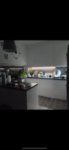 une cuisine avec des armoires blanches et une horloge au mur dans l'établissement Apartament Tarnowo Podgórne, à Tarnowo Podgórne