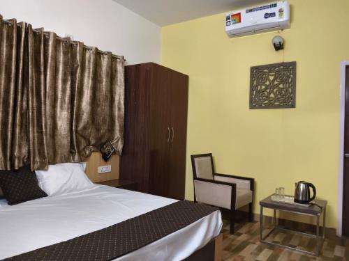 a bedroom with a bed and a chair and a window at Mohdev Resort in Jhājra