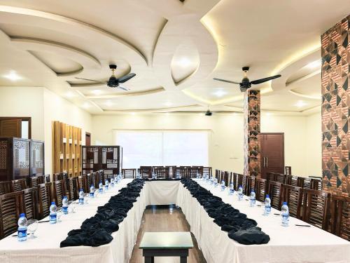 a banquet hall with long tables with black chairs at Hotel One University Sukkur in Sukkur