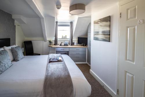 a bedroom with a large white bed and a desk at The Cumberland in Weymouth