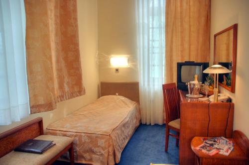a room with a bed and a table and a television at Garni Hotel Park in Palić