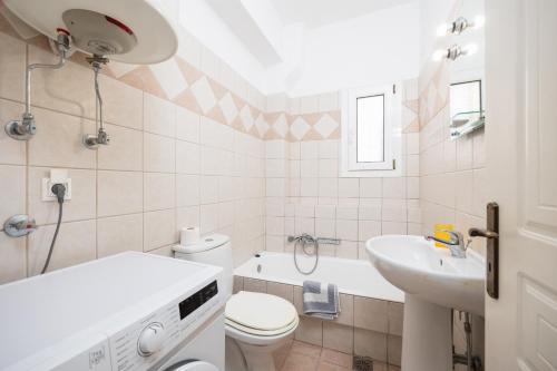 a white bathroom with a toilet and a sink at Skala Villa Yellow in Skala Kefalonias