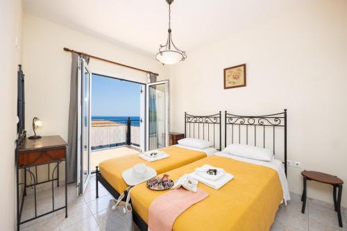 two beds in a room with a view of the ocean at Skala Villa Yellow in Skala Kefalonias