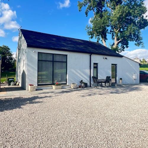 a white building with two chairs in front of it at Thwaite Croft - Carnforth in Carnforth