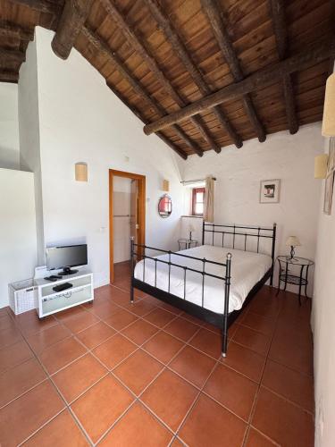 a bedroom with a bed and a flat screen tv at Casinha do Chafariz - Casas da Amieira in Amieira