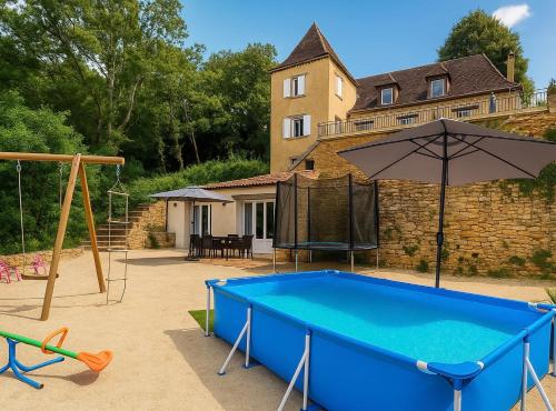 une cour arrière avec une piscine bleue et un parasol dans l'établissement Gîte Le Vélo Rouge - Airco & Parking, à Sarlat-la-Canéda