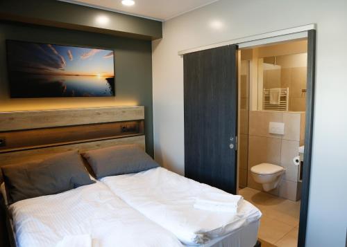 1 dormitorio con cama, aseo y TV en Gistihúsið Hofsósi, en Hofsós