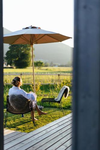 a woman sitting in a chair under an umbrella at Agrad Chalets in Aschau im Chiemgau