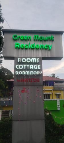 a sign for a green mouse restaurant and a building at Greenmount Residency in Marayoor