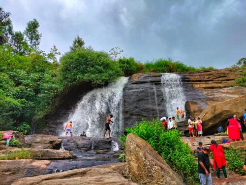 a group of people standing in front of a waterfall at Greenmount Residency in Marayoor
