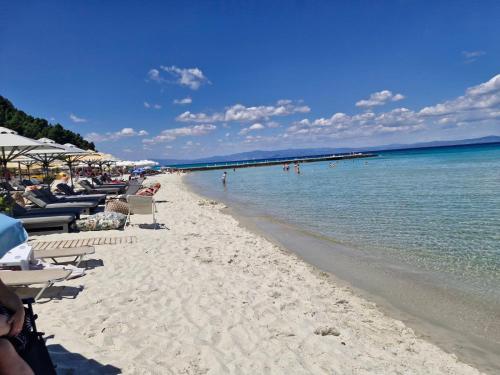 a beach with chairs and people in the water at Relax Dream Villa-House, Apartement, Studio in Kallithea Halkidikis