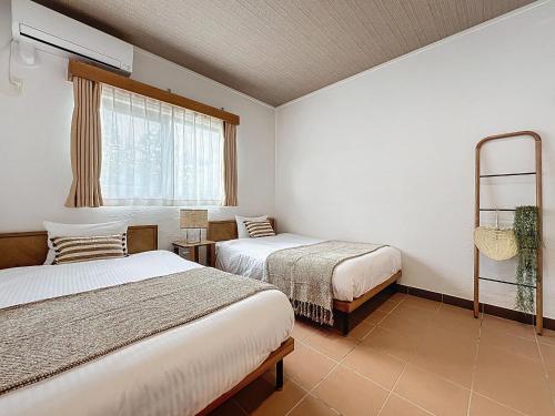 a bedroom with two beds and a window at ulu Okinawa Resort in Motobu