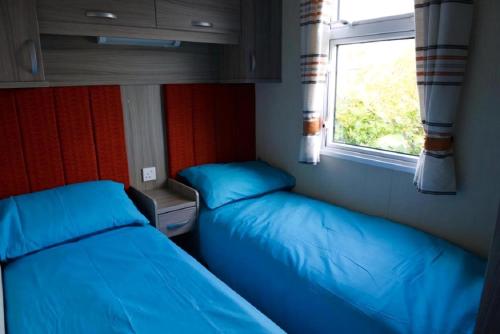 two beds in a small room with a window at Stunning 6 Berth Caravan For Hire At Norfolks Seashore Haven Park Ref 22005Ev in Great Yarmouth