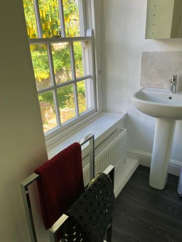 a bathroom with a sink and a window and a chair at Temple Croft Bed and Breakfast in Alston